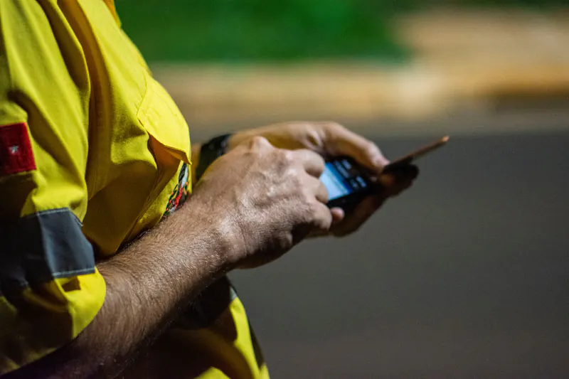 Worker in a hi-vis shirt reading a text on his phone
